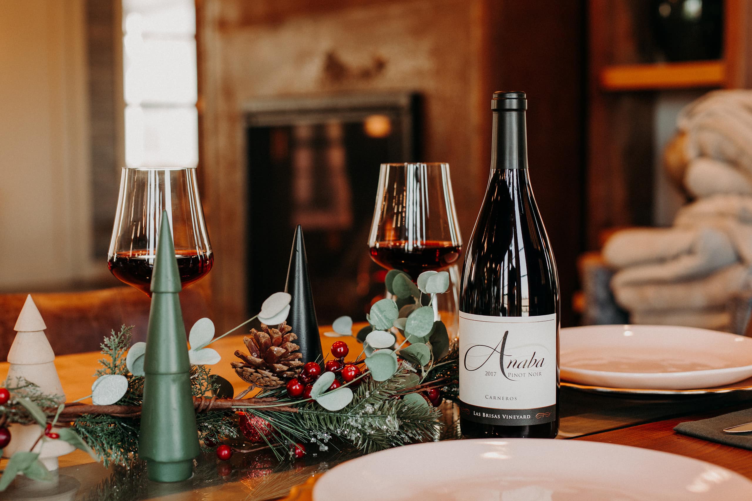 A bottle of Anaba Pinot Noir sits on a decorated dinner table.